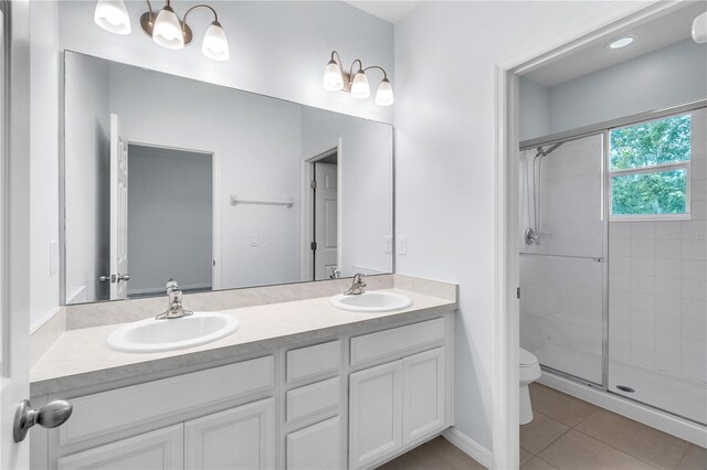 bathroom with a sink, tile patterned floors, a stall shower, and toilet