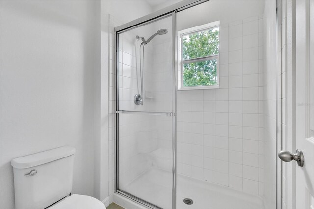 bathroom with a shower stall and toilet