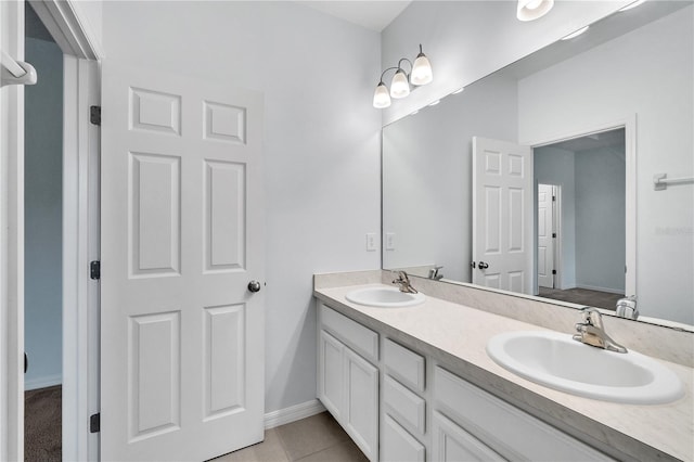 bathroom with a sink, baseboards, tile patterned floors, and double vanity