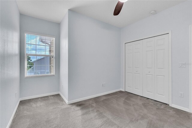 unfurnished bedroom featuring carpet floors, baseboards, a ceiling fan, and a closet