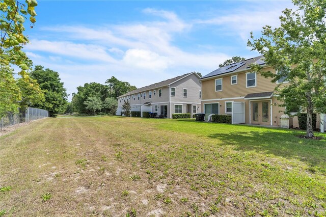 back of property featuring a yard, fence, and french doors