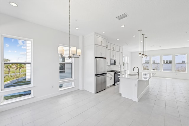 kitchen with gas stove, freestanding refrigerator, open floor plan, and a chandelier