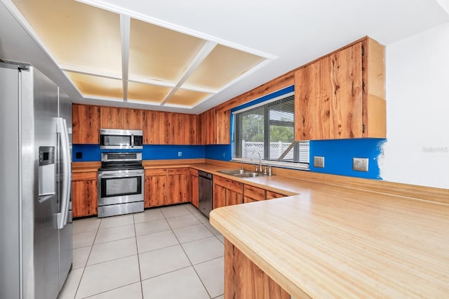 3379 Monika Cir, Orlando, FL 32812 - kitchen with a peninsula, light countertops, brown cabinets, a sink, and stainless steel appliances