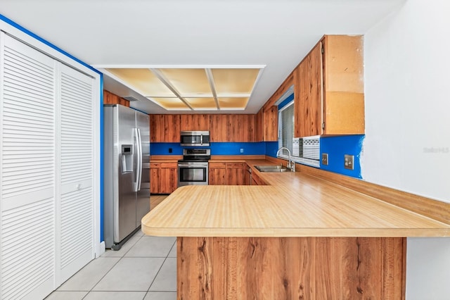 3379 Monika Cir, Orlando, FL 32812 - kitchen with appliances with stainless steel finishes, a sink, light countertops, brown cabinetry, and a peninsula