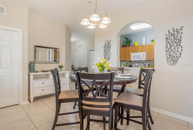 dining area with light tile patterned floors, a notable chandelier, visible vents, and arched walkways