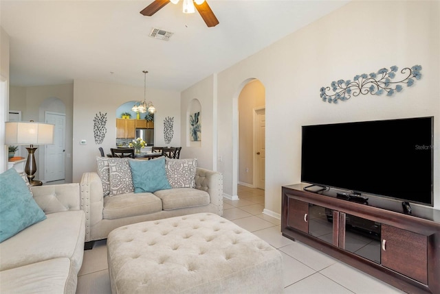 living room featuring ceiling fan with notable chandelier, visible vents, arched walkways, light tile patterned floors, and baseboards