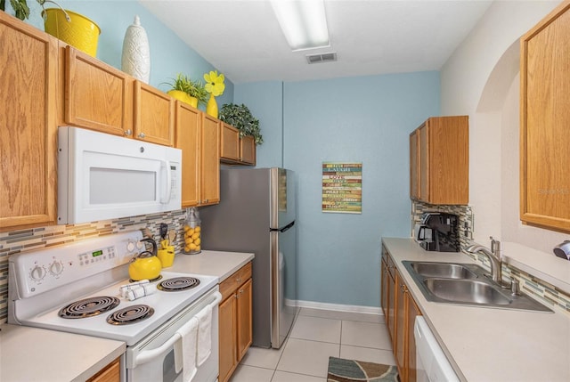 kitchen with a sink, white appliances, visible vents, decorative backsplash, and light countertops