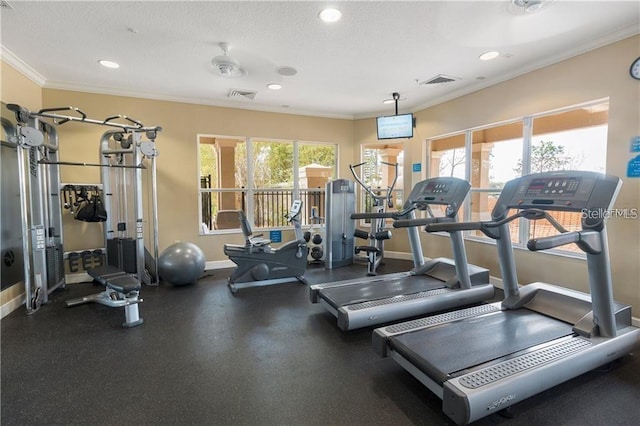 gym with baseboards, a wealth of natural light, crown molding, and visible vents