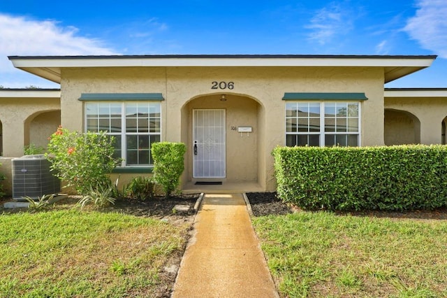 206 Diamond Cv Unit 106, Casselberry, FL 32707 - entrance to property featuring central air condition unit, stucco siding, and a lawn