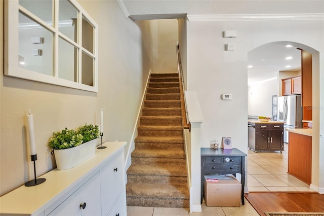 stairs featuring arched walkways, ornamental molding, and tile patterned flooring