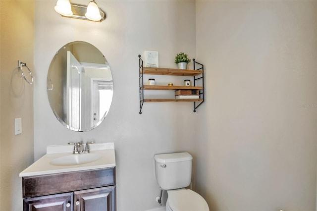 bathroom featuring toilet, baseboards, and vanity