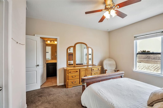 carpeted bedroom with ensuite bathroom and a ceiling fan