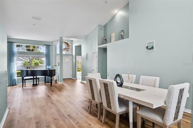 633 Lakehaven Cir, Orlando, FL 32828 - dining space featuring a towering ceiling, baseboards, a chandelier, and light wood finished floors