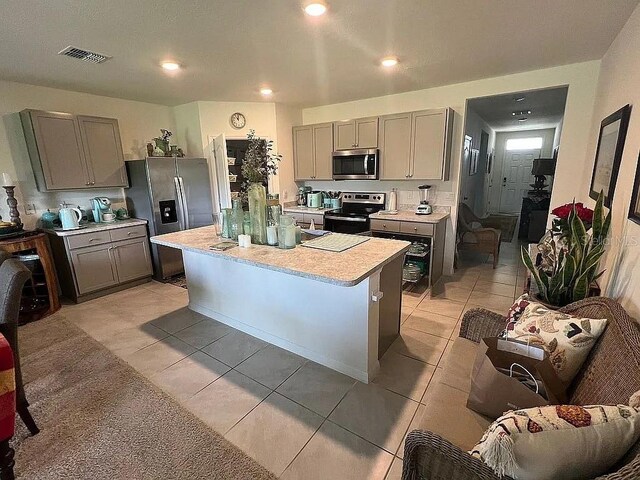2711 Neverland Dr, New Smyrna Beach, FL 32168 - kitchen with stainless steel appliances, light countertops, light tile patterned floors, and gray cabinets