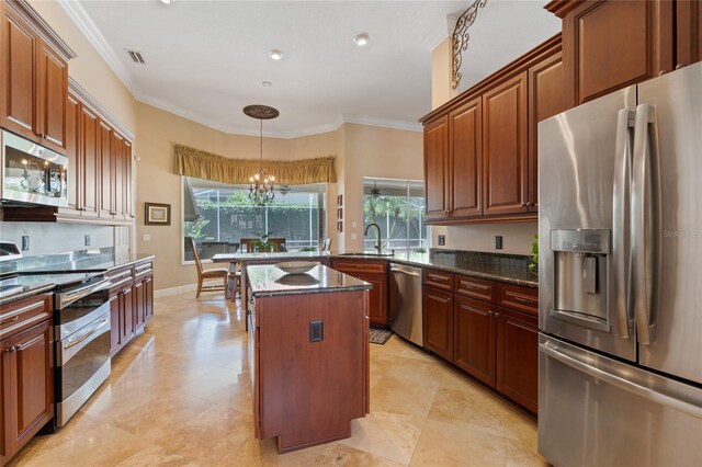 2232 Lake Vilma Dr, Orlando, FL 32835 - kitchen with visible vents, appliances with stainless steel finishes, a peninsula, dark stone countertops, and ornamental molding