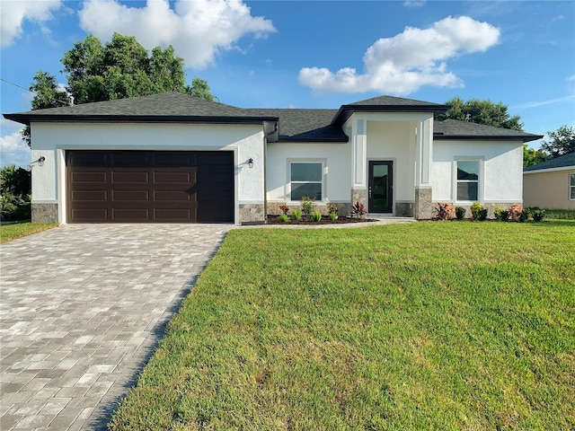 prairie-style house with a front yard, decorative driveway, an attached garage, stone siding, and stucco siding