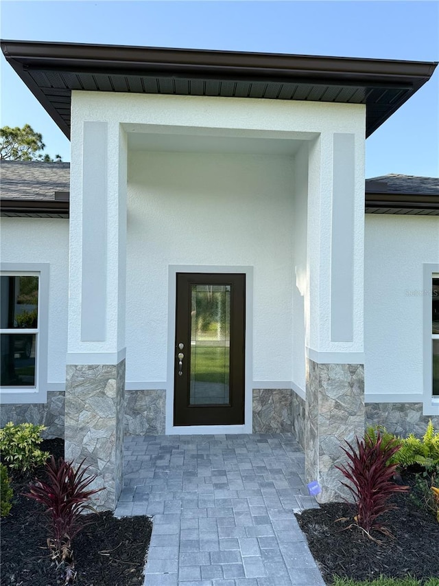 view of exterior entry with stucco siding and stone siding