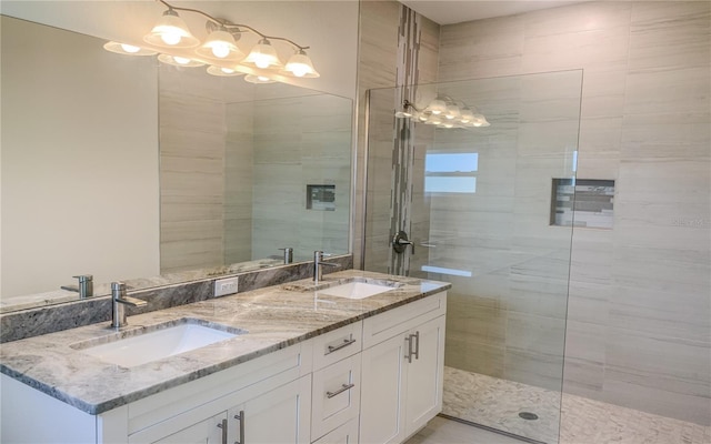 full bath featuring a sink, double vanity, and tiled shower