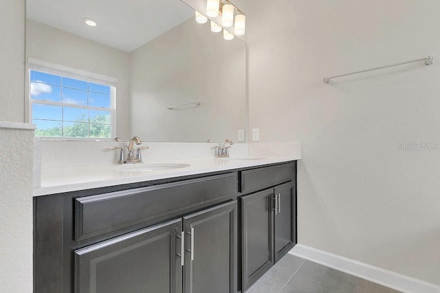 bathroom featuring a sink, baseboards, tile patterned flooring, and double vanity