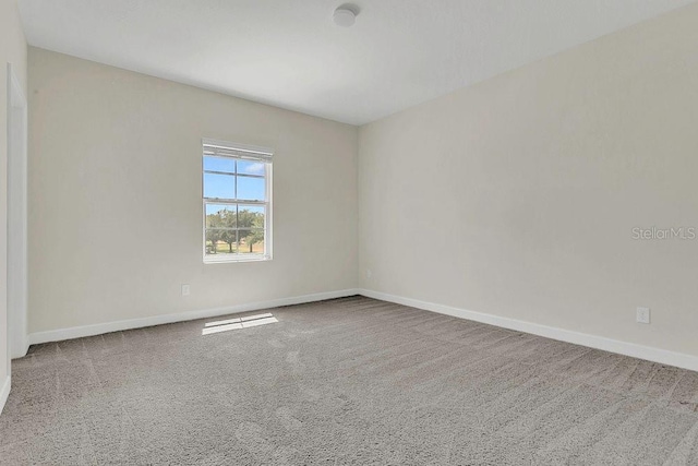 carpeted spare room featuring baseboards