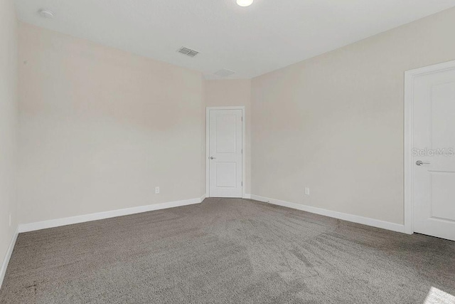 empty room featuring visible vents, carpet, and baseboards