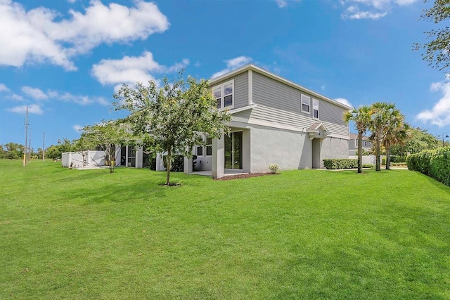 back of house featuring stucco siding and a yard