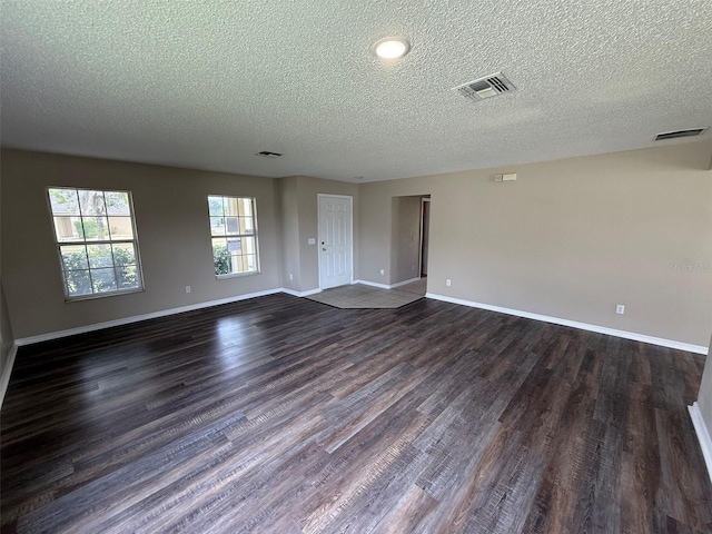 unfurnished room with dark wood-style flooring, a textured ceiling, visible vents, and baseboards
