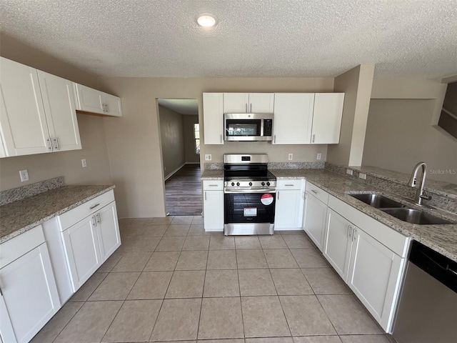 kitchen with stainless steel appliances, a textured ceiling, and a sink