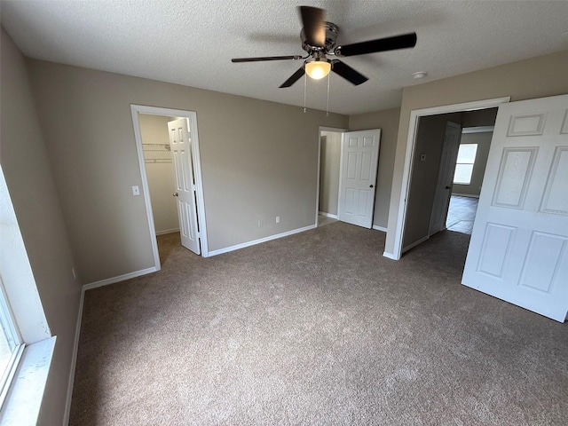 unfurnished bedroom featuring baseboards, dark colored carpet, and a textured ceiling