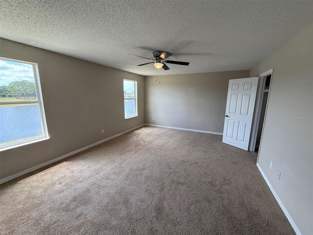 spare room featuring a ceiling fan, baseboards, carpet, and a textured ceiling
