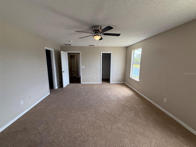 empty room with visible vents, baseboards, a textured ceiling, a ceiling fan, and carpet
