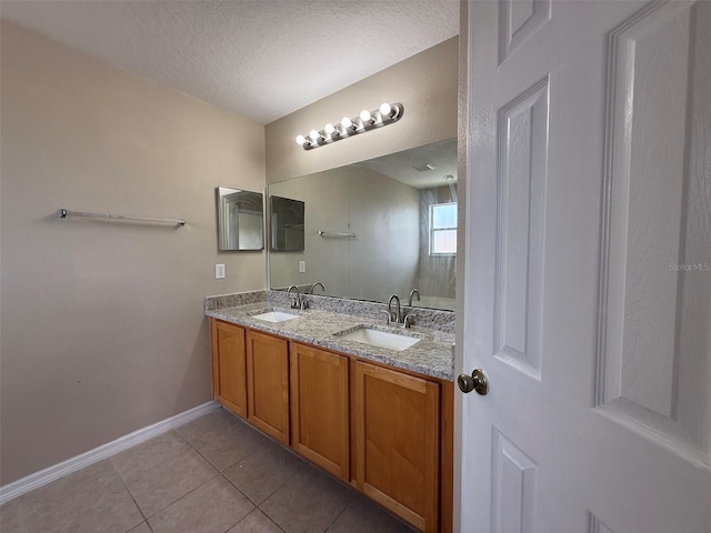 bathroom with baseboards, a textured ceiling, tile patterned floors, and a sink