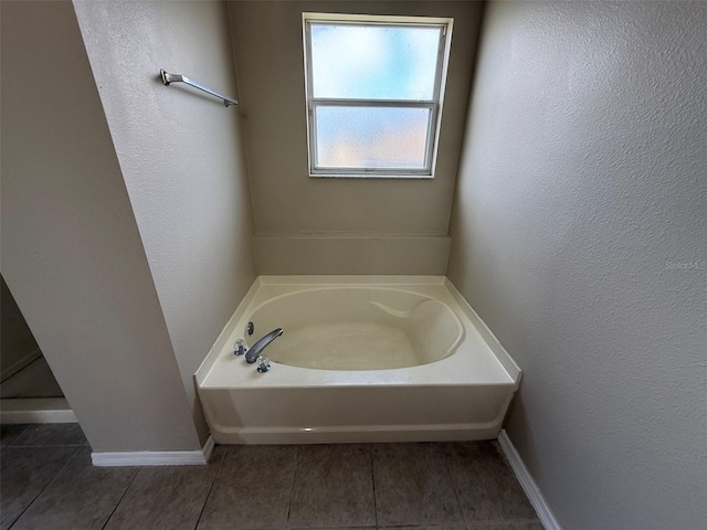 bathroom with baseboards, tile patterned flooring, a garden tub, and a textured wall