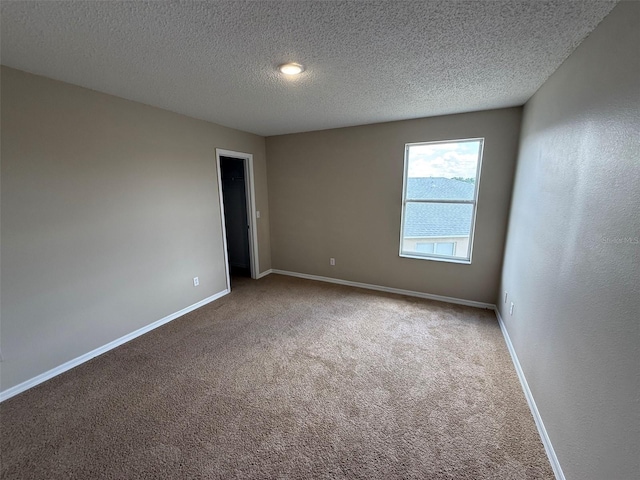 carpeted empty room featuring baseboards and a textured ceiling
