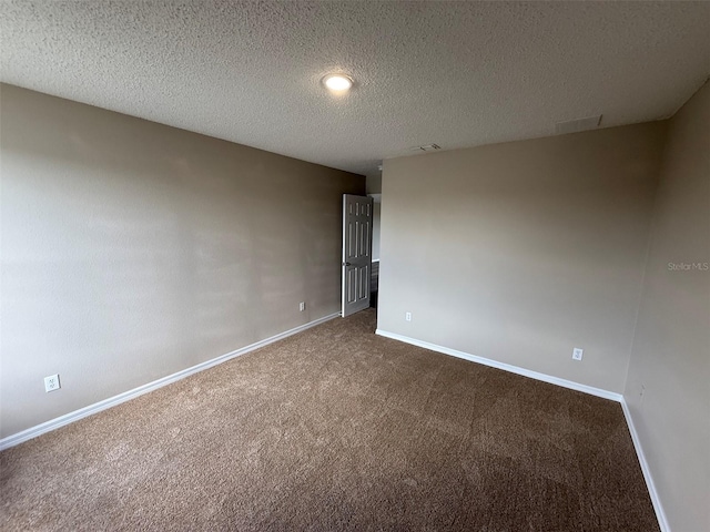 carpeted spare room with a textured ceiling, baseboards, and visible vents