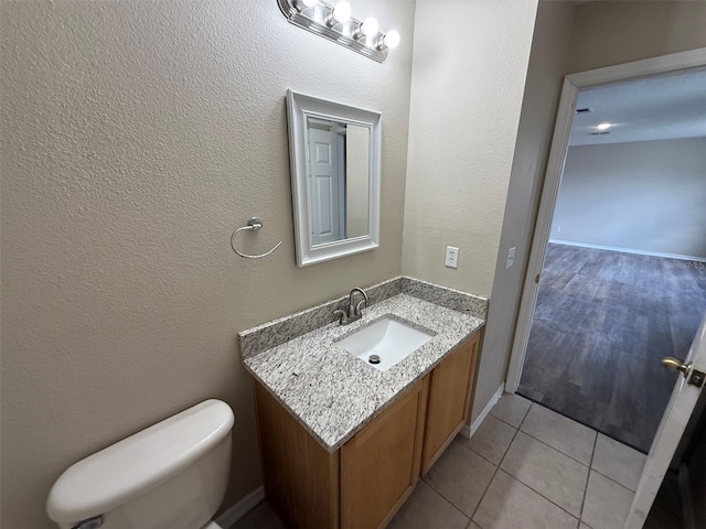 half bath with vanity, tile patterned floors, and toilet