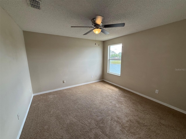 carpeted empty room featuring visible vents, a ceiling fan, baseboards, and a textured ceiling