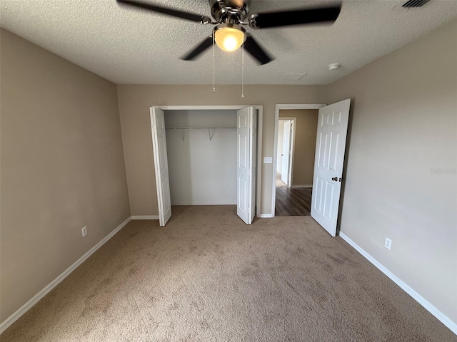 unfurnished bedroom with carpet floors, a textured ceiling, baseboards, and a closet