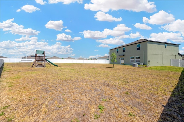 view of yard with central AC, a fenced backyard, and a playground