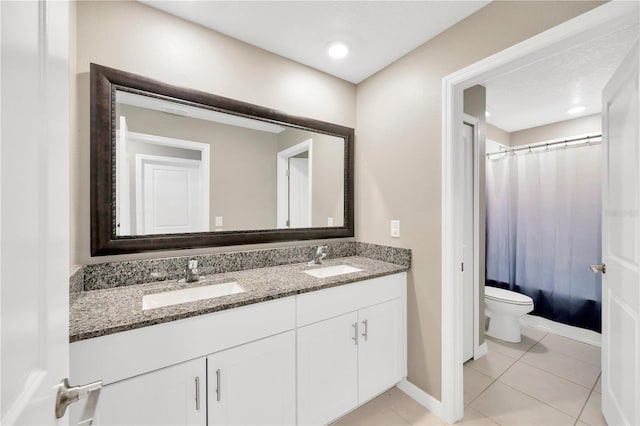 bathroom featuring a sink, tile patterned flooring, toilet, and double vanity