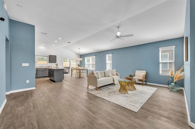 1397 Gatlin Pl, The Villages, FL 32163 - living room featuring ceiling fan with notable chandelier, baseboards, wood finished floors, vaulted ceiling, and visible vents