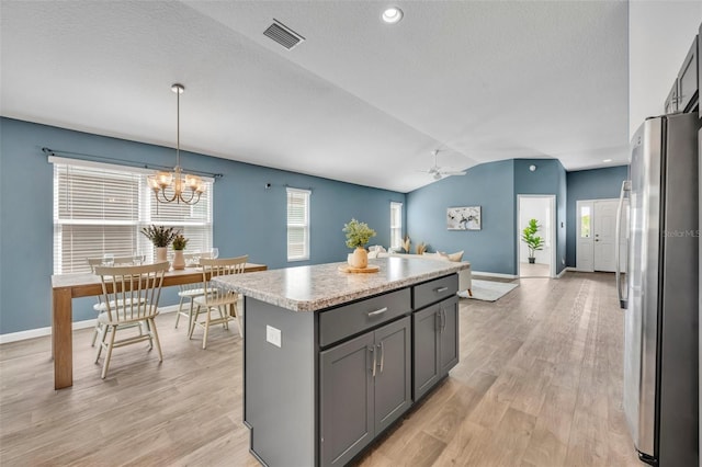 1397 Gatlin Pl, The Villages, FL 32163 - kitchen with a kitchen island, visible vents, vaulted ceiling, freestanding refrigerator, and ceiling fan with notable chandelier