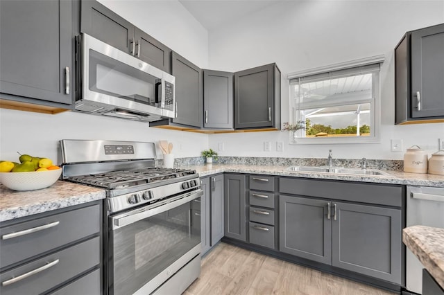 1397 Gatlin Pl, The Villages, FL 32163 - kitchen with light stone countertops, light wood-type flooring, a sink, appliances with stainless steel finishes, and gray cabinetry