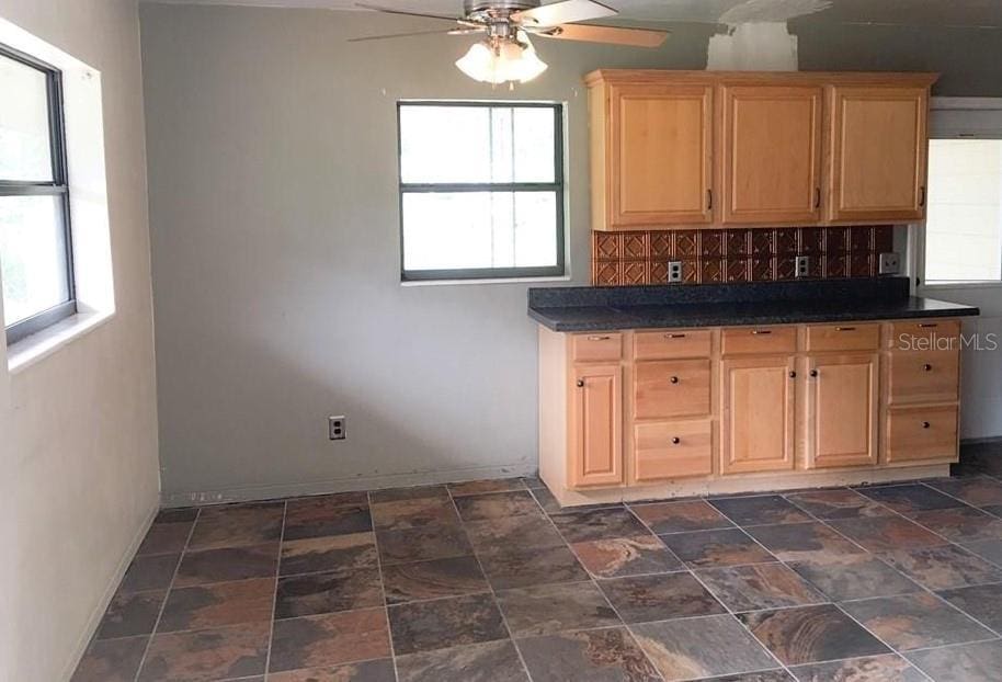3015 Ave I NW, Winter Haven, FL 33881 - kitchen featuring a healthy amount of sunlight, dark countertops, light brown cabinets, and ceiling fan