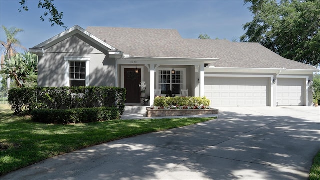 view of front facade featuring roof with shingles, an attached garage, driveway, and stucco siding