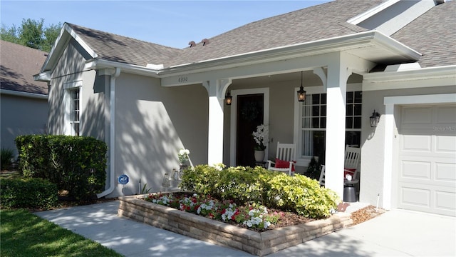 view of exterior entry with an attached garage, stucco siding, and covered porch