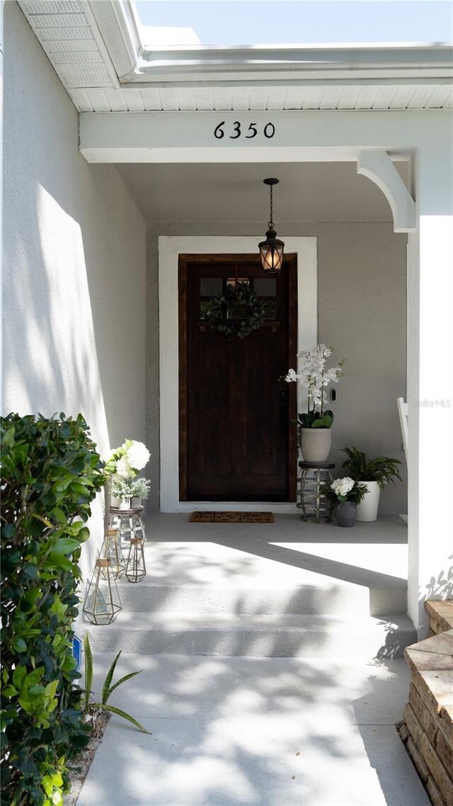 property entrance with stucco siding and covered porch