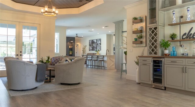 bar featuring wine cooler, an inviting chandelier, a bar, and light wood-type flooring