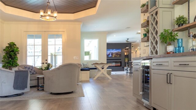 interior space featuring beverage cooler, a glass covered fireplace, light wood-style flooring, and wood ceiling