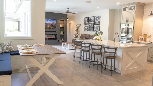 kitchen featuring crown molding, light wood finished floors, stainless steel double oven, and open floor plan